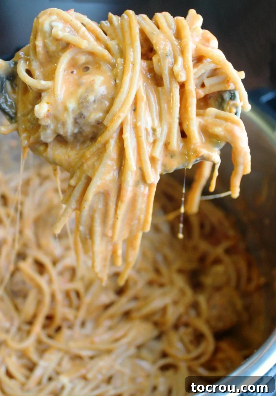 Instant Pot Magic: Creamy One-Pot Meatball Spaghetti 3 A serving spoon lifting a generous portion of steaming hot, creamy spaghetti and meatballs from an Instant Pot, showcasing its rich texture.