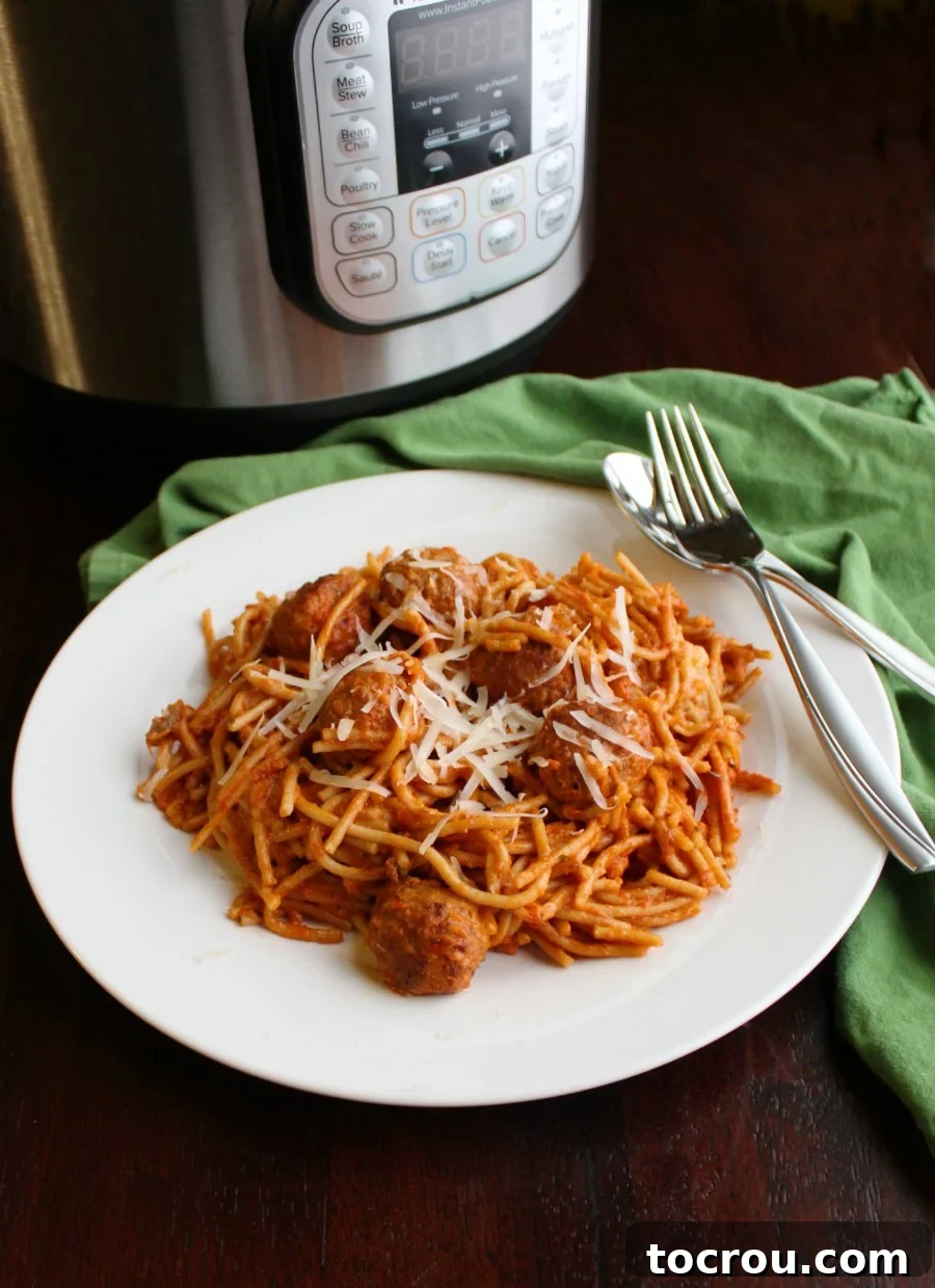 Instant Pot Magic: Creamy One-Pot Meatball Spaghetti 4 A delicious serving of spaghetti and meatballs, garnished with grated Parmesan cheese, presented in front of the pressure cooker it was prepared in.