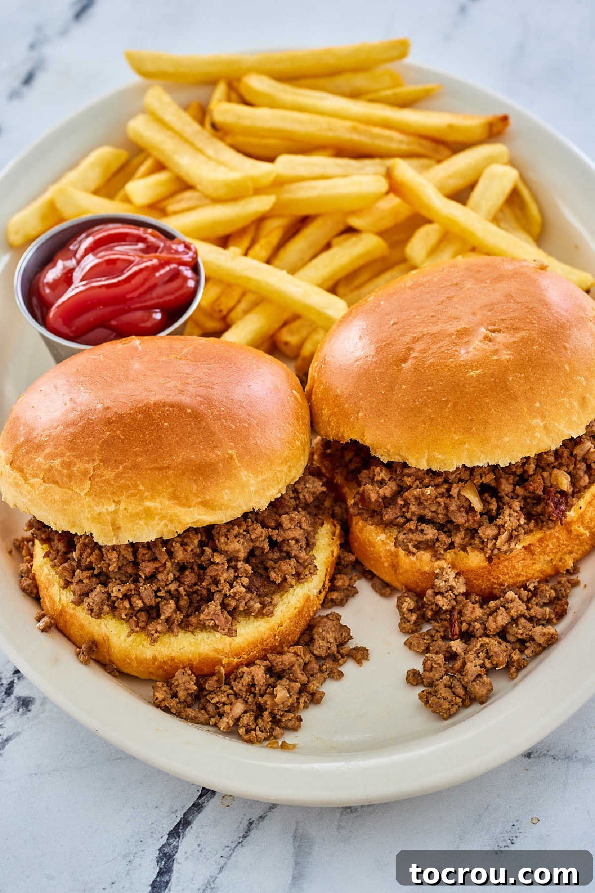Plate with two homemade made right sandwiches served with fries and ketchup.
