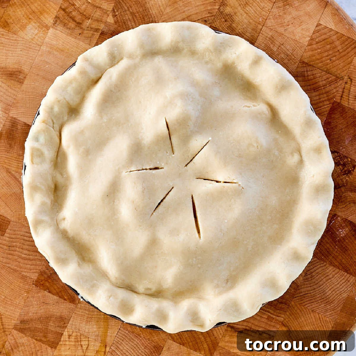 Golden-brown, flaky lard pie crust pastry gracefully fitted over a rustic apple pie filling, featuring classic vent holes in the center, perfectly poised for baking in the oven.