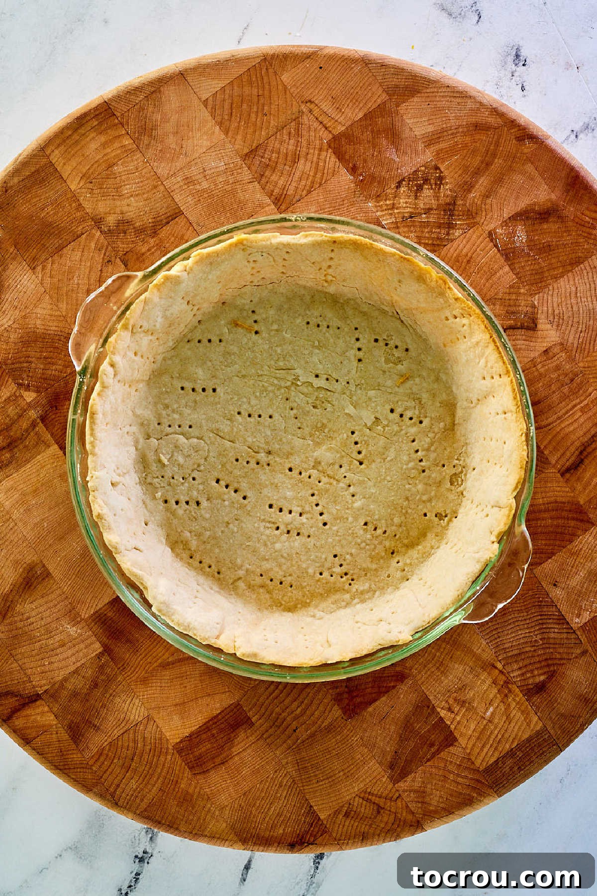A perfectly blind-baked pie crust, fresh from the oven, showcasing a beautiful golden-brown hue and subtle fork prick marks on its bottom surface.