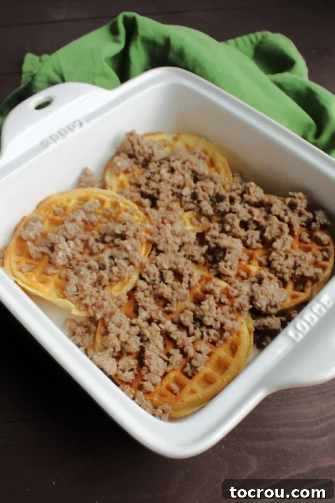 Sausage Layer on Waffles Crumbled breakfast sausage sprinkled evenly over a layer of waffles in the bottom of a baking dish.