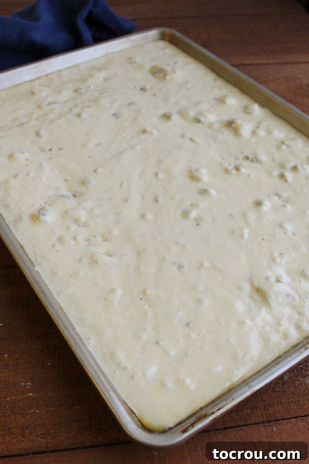 Sheet pan filled with pancake batter with dots of breakfast sausage, ready to bake.
