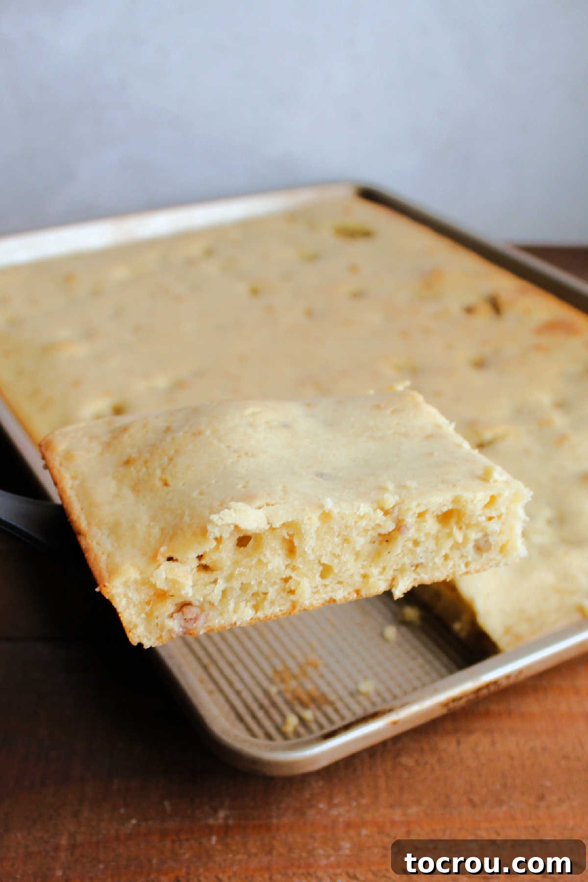 Lifting piece of sausage sheet pan pancake out of sheet pan with a spatula.