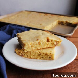 stack of two square slices of sheet pan pancake with chunks of breakfast sausage baked inside.