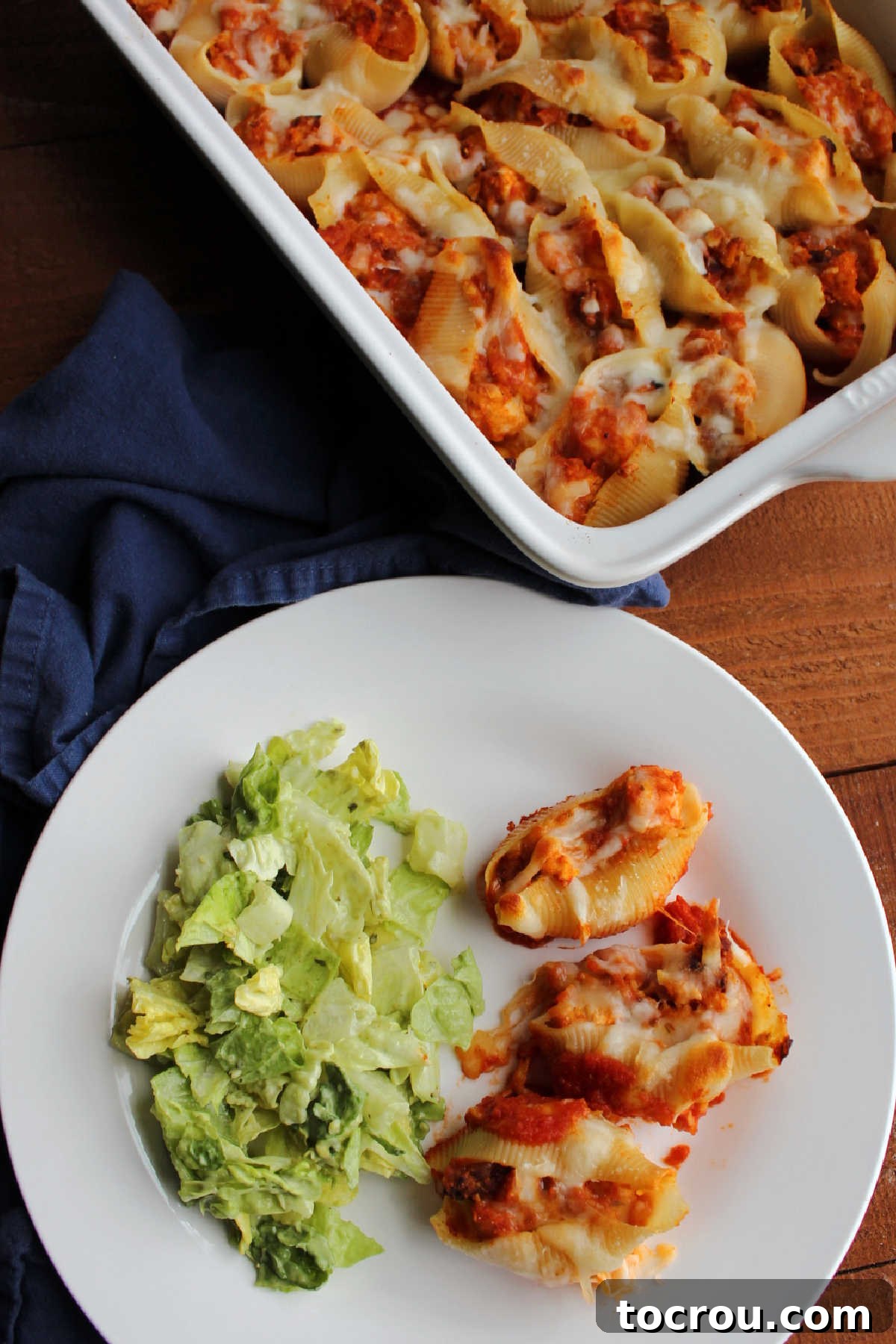 Chicken parmesan stuffed shells served on a plate with a fresh green salad.