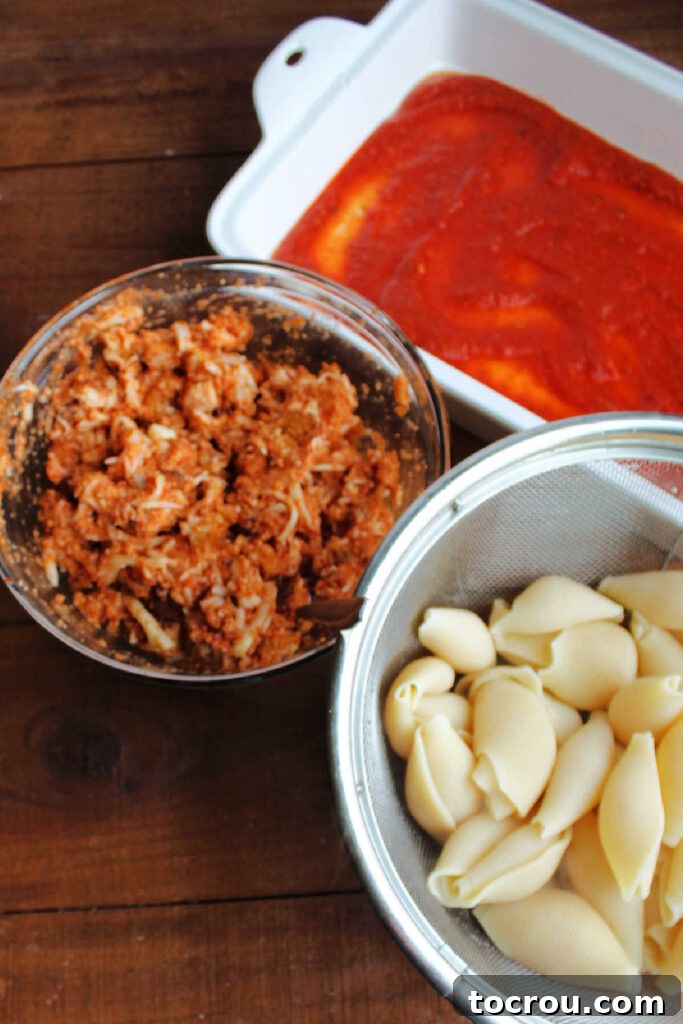 Large cooked pasta shells next to a pan, ready to be filled with the chicken parmesan mixture.