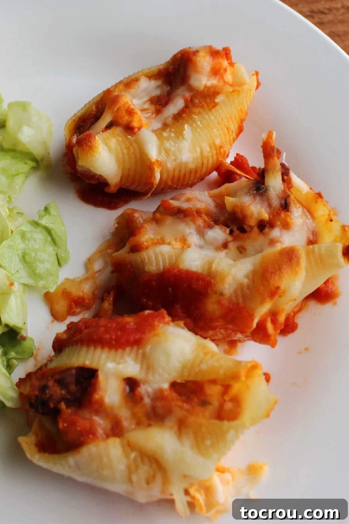 Close up of chicken parmesan baked shells on a dinner plate, ready to eat.