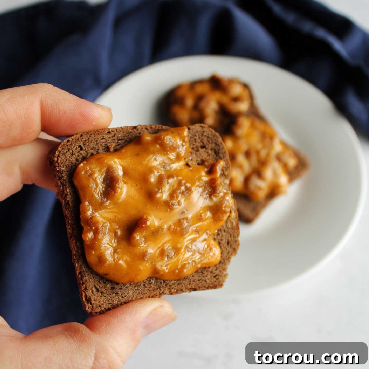 Whip up a batch of party ryes for a fun pizza inspired appetizer later. Once batch makes a ton of flatbreads and they freeze great to bake later. Hand holding a freshly baked, pizza-flavored party rye appetizer, ready to eat.