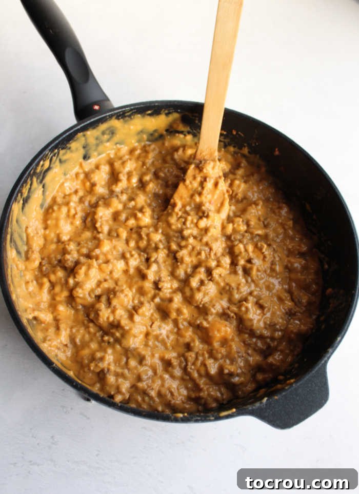 Rye Pizza Party Bites 2 Large skillet filled with browned sausage crumbles and melted Velveeta cheese, ready to be spread on rye bread slices.