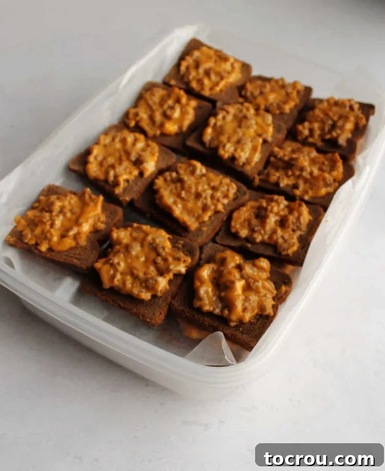 Rye Pizza Party Bites 3 Plastic storage container showing layers of party ryes with wax paper in between, prepared for freezing.