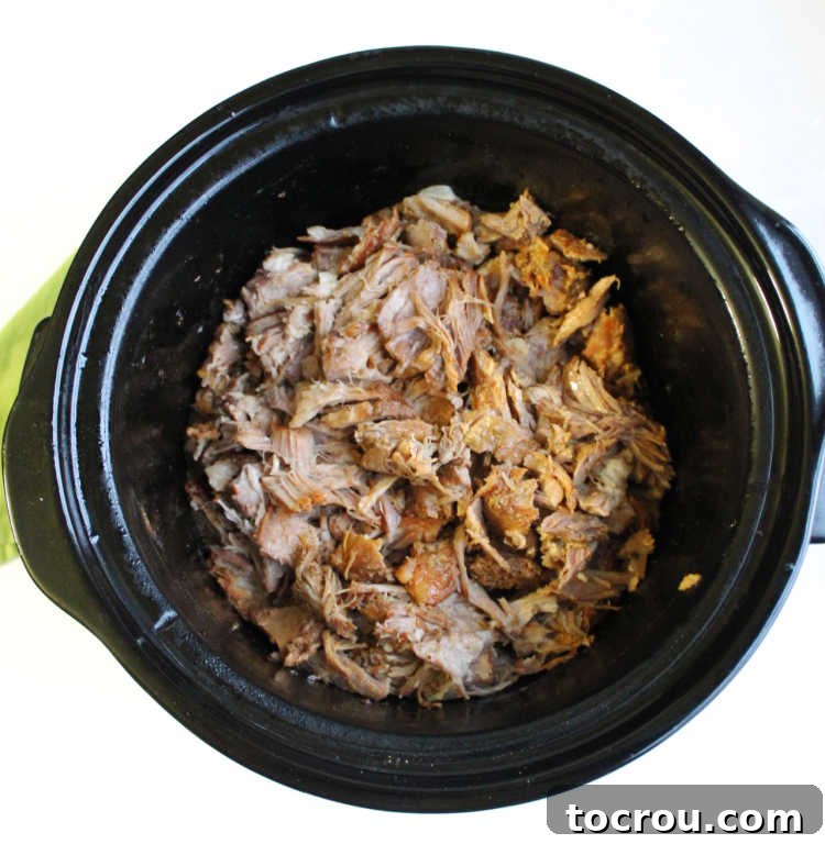 Luau Slow Cooker Pulled Pork 3 Freshly pulled pineapple pork shoulder in slow cooker, ready to serve, with a rich, glossy sauce.