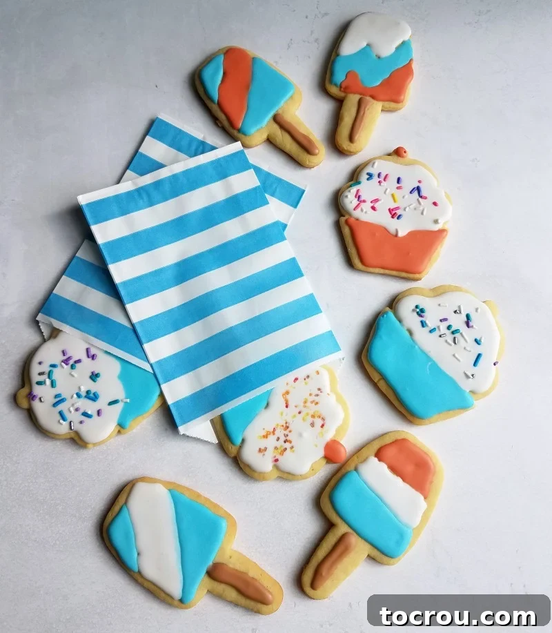 Sugar cookies cut into the shapes of popsicles and cupcakes decorated with red white and blue royal icing.