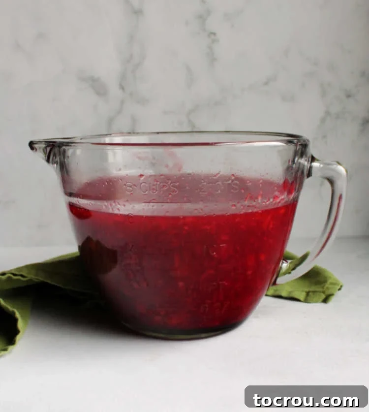 Tropical Cherry Fluff Salad 3 Glass mixing bowl containing the vibrant red jello, cherry, and pineapple mixture, ready to be chilled