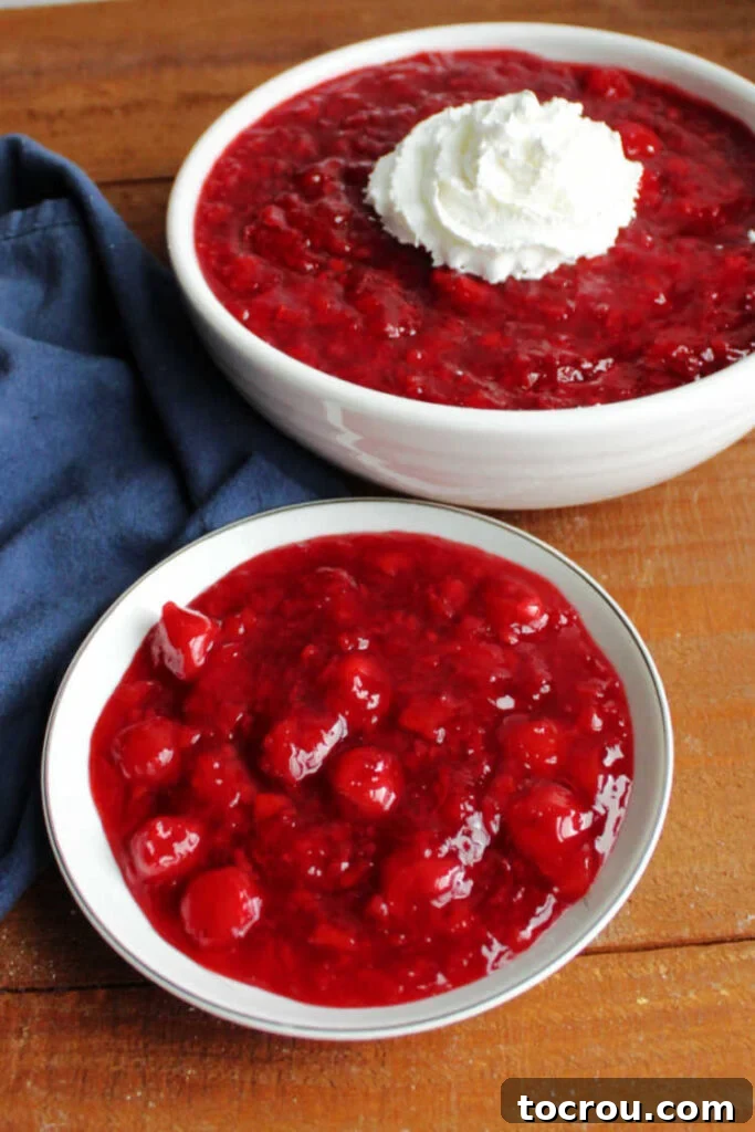 Tropical Cherry Fluff Salad 5 Small bowl of cherry jello salad with a larger serving bowl filled with the same salad in the background