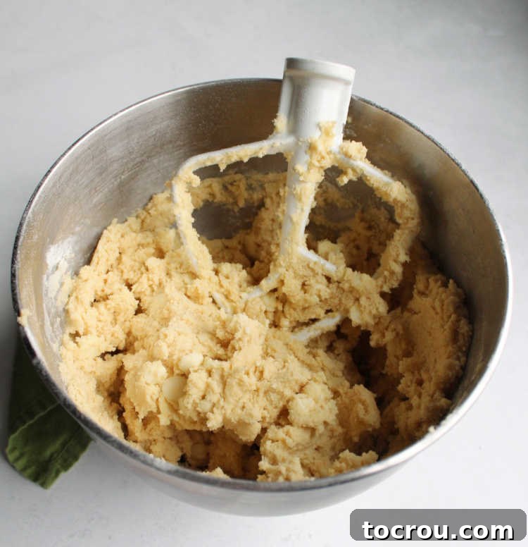 Mixer bowl filled with creamy white hot chocolate mix cookie dough, ready for baking.