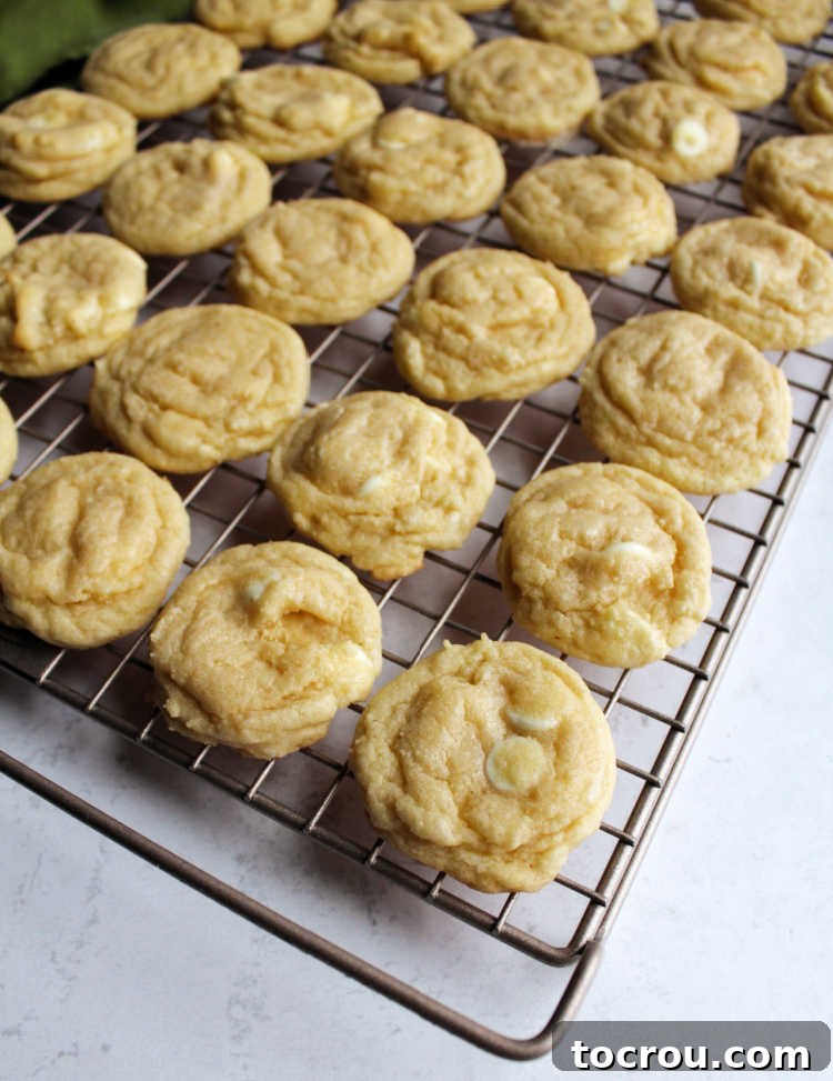 Warm white hot chocolate cookies cooling on a wire rack, steam gently rising.