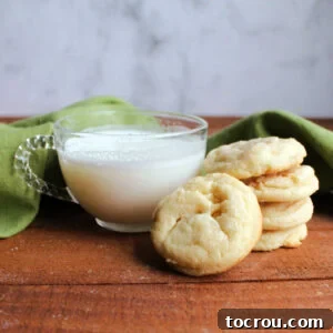 stack of white hot chocolate cookies next to small glass mug of white hot chocolate.