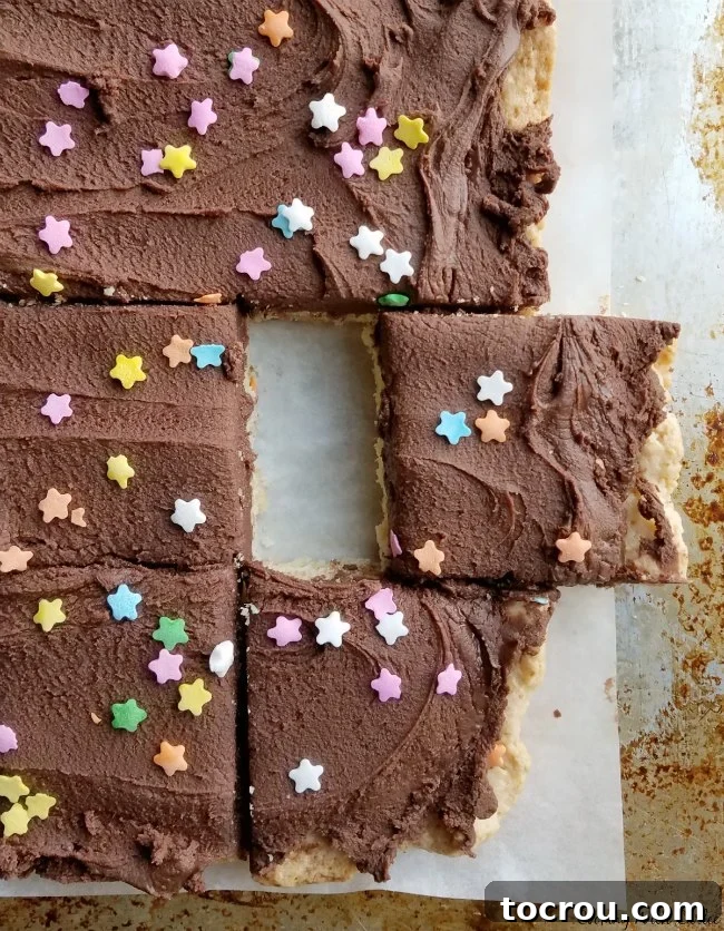 Chocolate frosting topped sugar cookie bars cut into squares with one pulled out, showing the soft interior.
