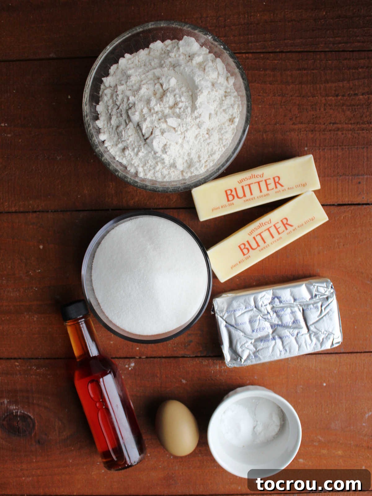 Ingredients for soft sugar cookie bars including butter, cream cheese, flour, sugar, egg, baking soda, baking powder, and vanilla, laid out on a counter.