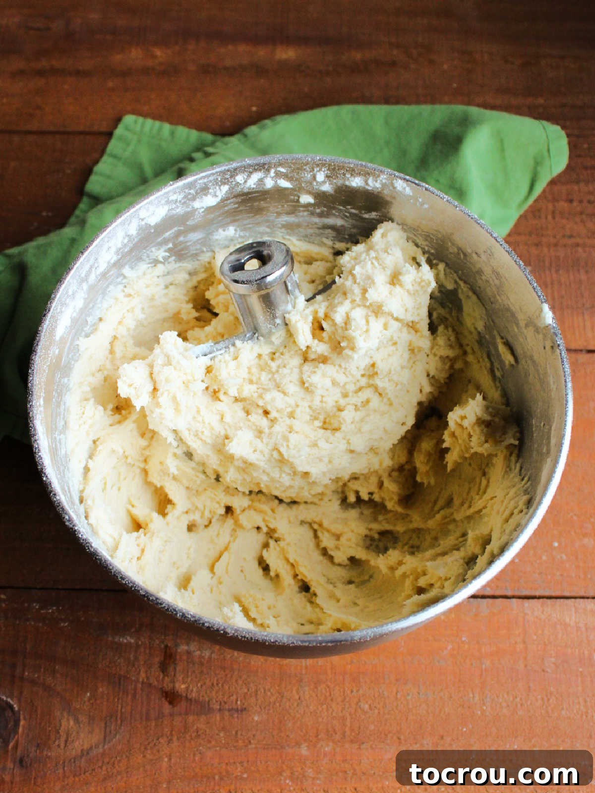 Mixer bowl and paddle with soft, slightly sticky sugar cookie dough, indicating perfect consistency.