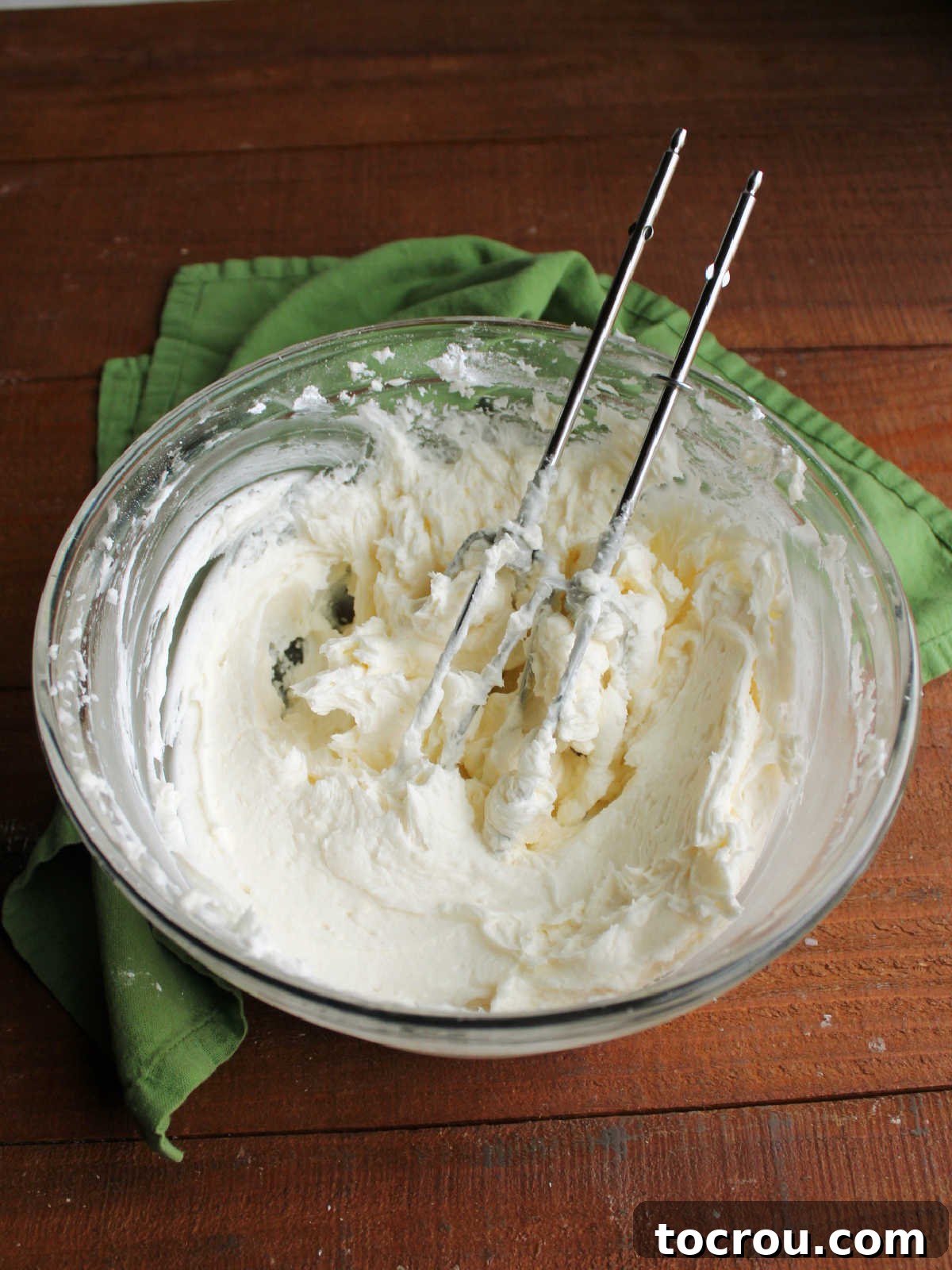 Glass bowl filled with fluffy white crusting buttercream, perfect for topping sugar cookie bars.