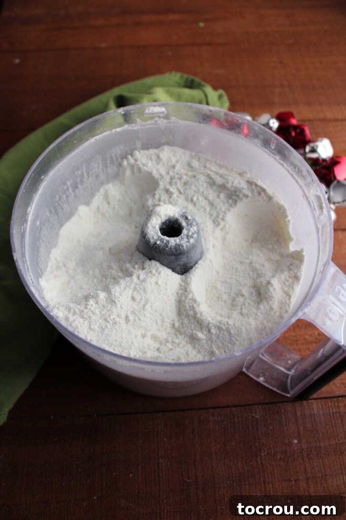A food processor bowl filled with finely ground powdery white hot chocolate mix, demonstrating the smooth consistency achieved during blending.