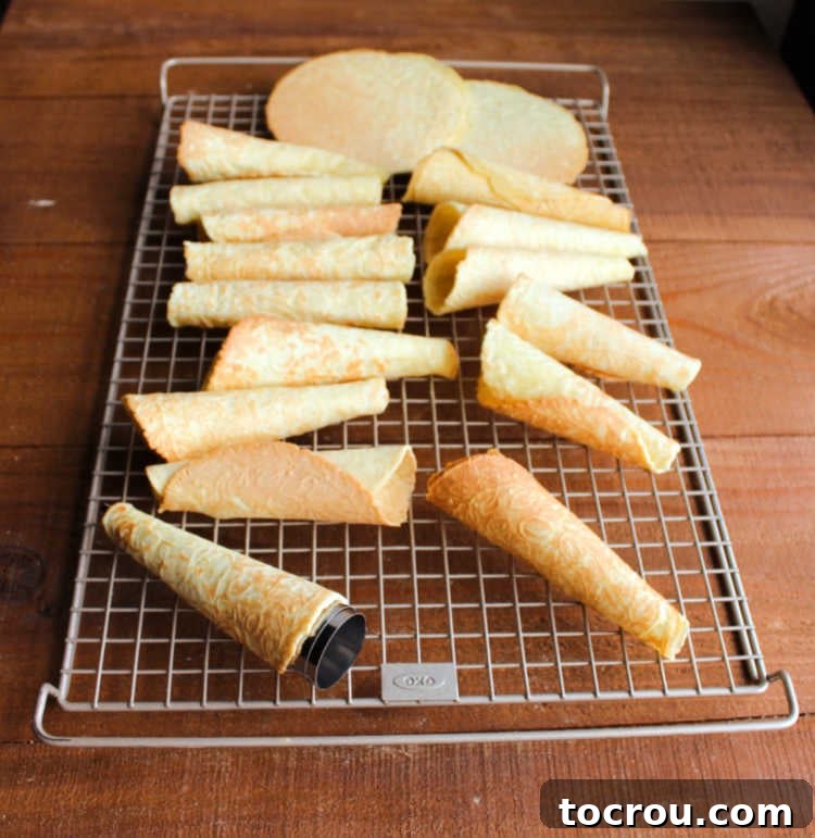 Freshly baked krumkake cooling on a wire rack, showing their delicate patterns.