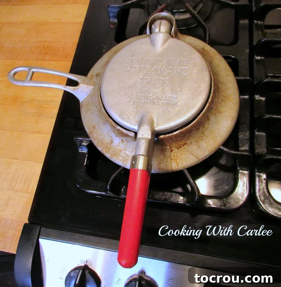 A vintage Nordic Ware krumkake iron heating on a stovetop, ready for baking.