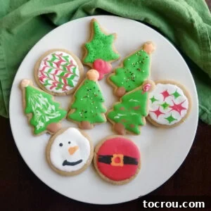 Peanut Butter Christmas Cookies A plate of delicious peanut butter cookies, cut into various Christmas shapes and expertly decorated with royal icing, ready for festive enjoyment.