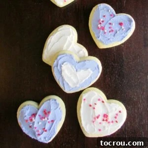 Sour Cream Heart Cookies Sour cream cookies cut into heart shapes, beautifully topped with buttercream frosting and festive sprinkles, ideal for celebrations.