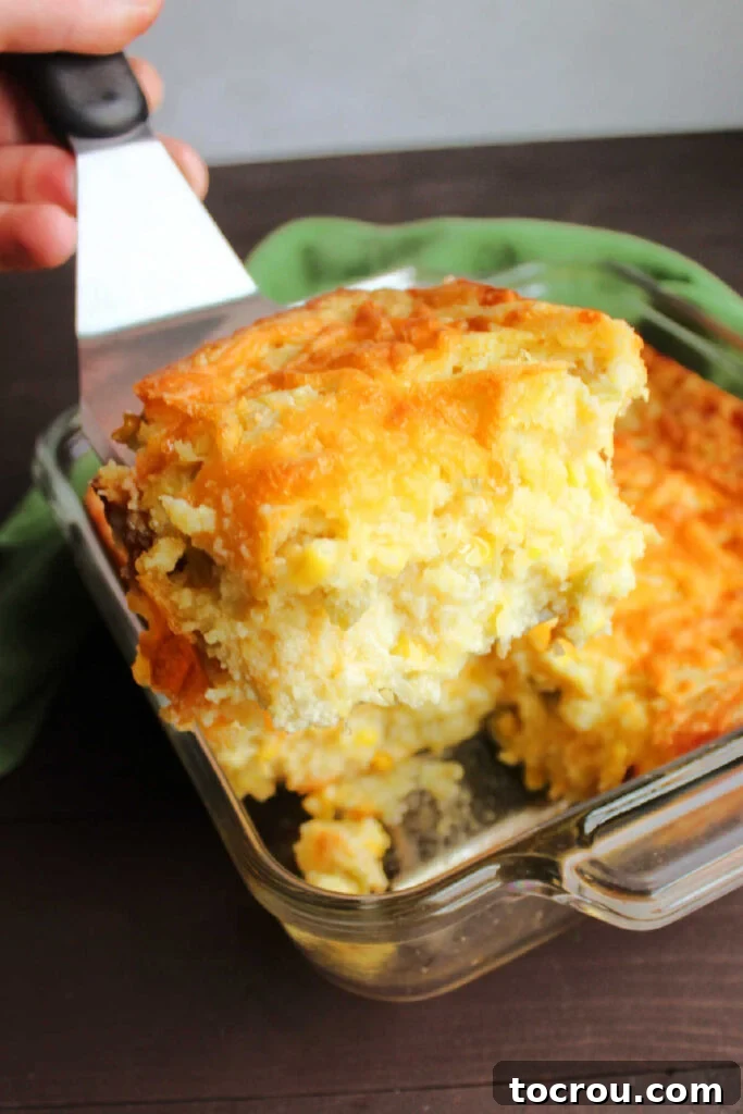 Soft and Cheesy Interior of Corn Casserole spatula lifting out slice of chili cheese corn casserole showing soft interior.