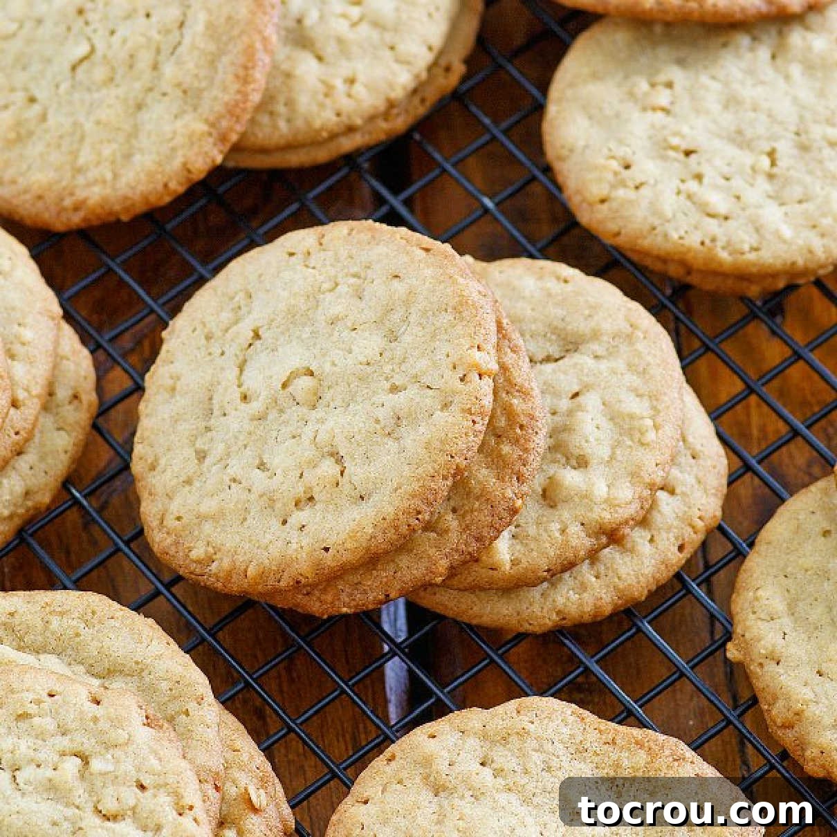 Close up of buttery ranger cookies on wire cooling rack showing their crisp edges and chewy centers.