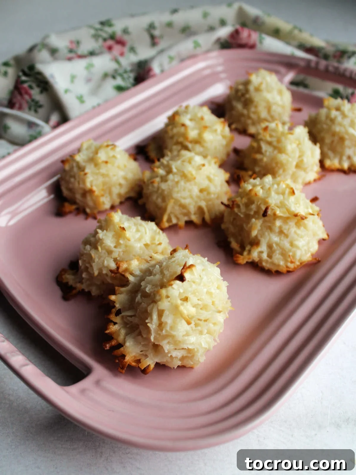 Irresistible Condensed Milk Coconut Bites 8 Pink platter of coconut macaroons showing golden brown edges and puffy white coconut cookies.