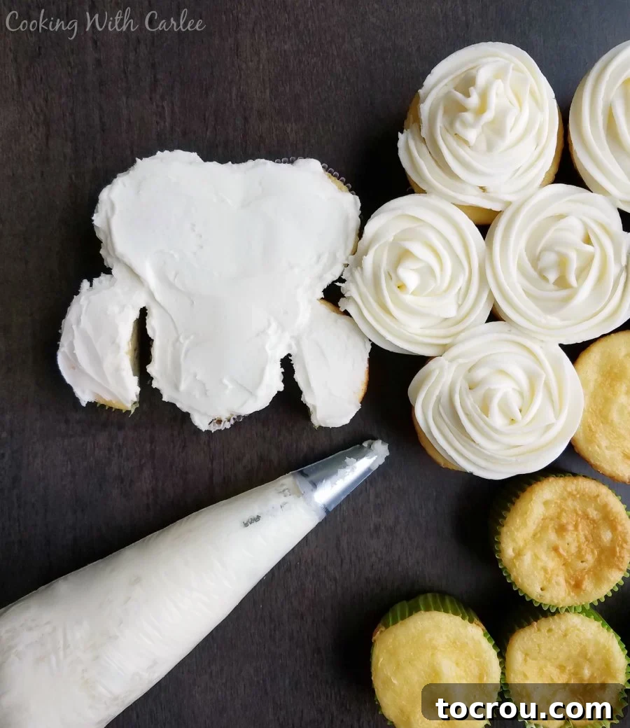 A close-up shot of a lamb-shaped cupcake cake being decorated with white American buttercream frosting to create fluffy wool texture.