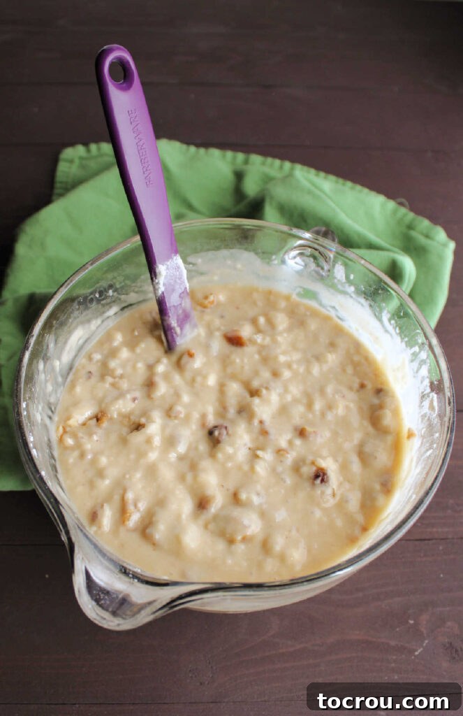 A mixing bowl filled with rich, textured date and walnut quick bread batter, ready for pouring.