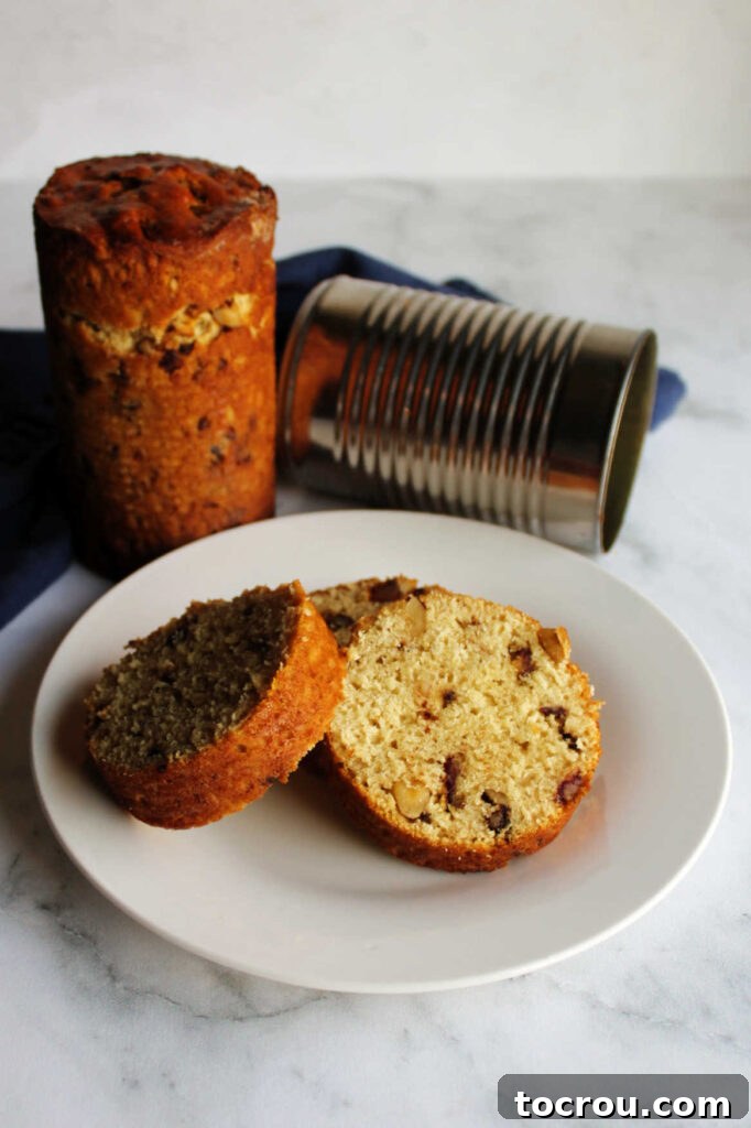 Slices of date nut bread arranged on a plate next to a whole loaf and an empty tin can, highlighting the unique presentation.