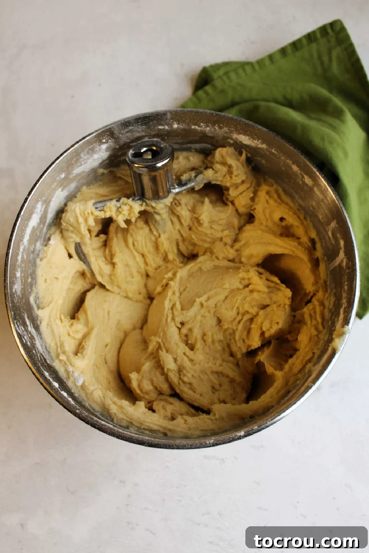 Mixing Sour Cream Cookie Dough to Perfection A mixer bowl containing perfectly mixed soft sour cream cookie dough, ready for baking, with a paddle attachment nearby.