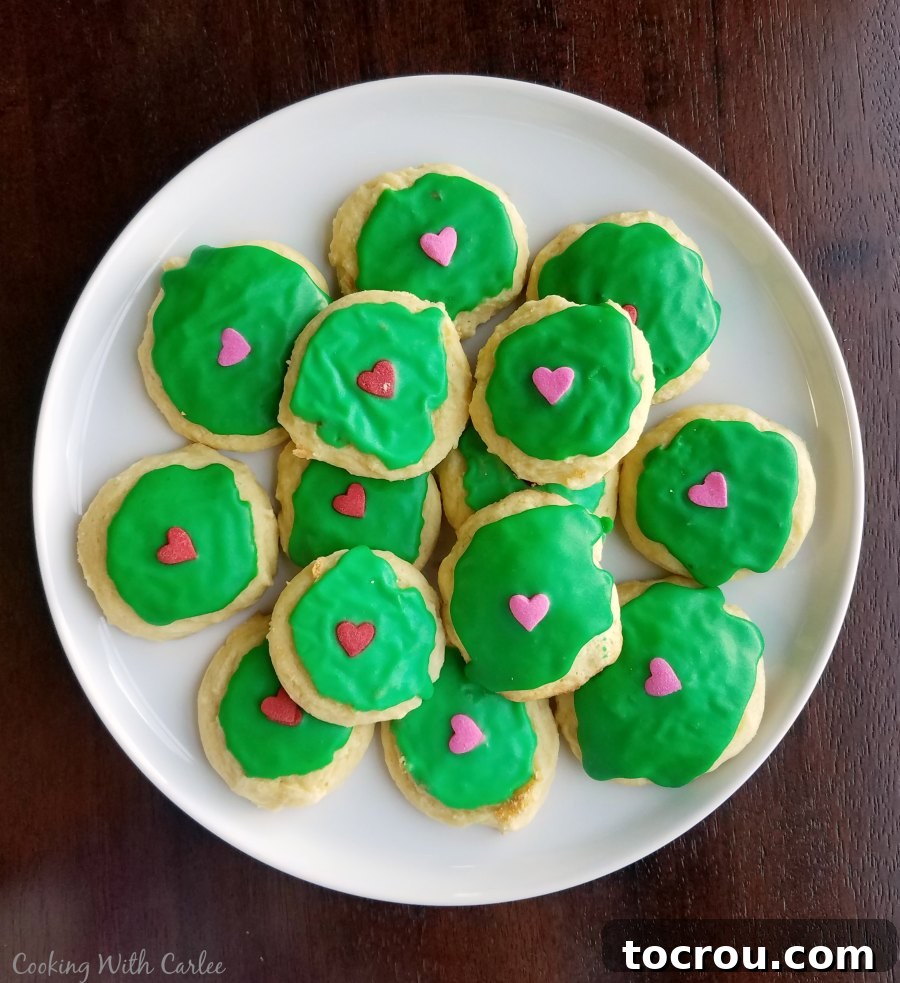 Festive Grinch Sour Cream Cookies Sour cream cookies decorated with green icing and candy hearts, inspired by the classic Grinch character for a festive treat.