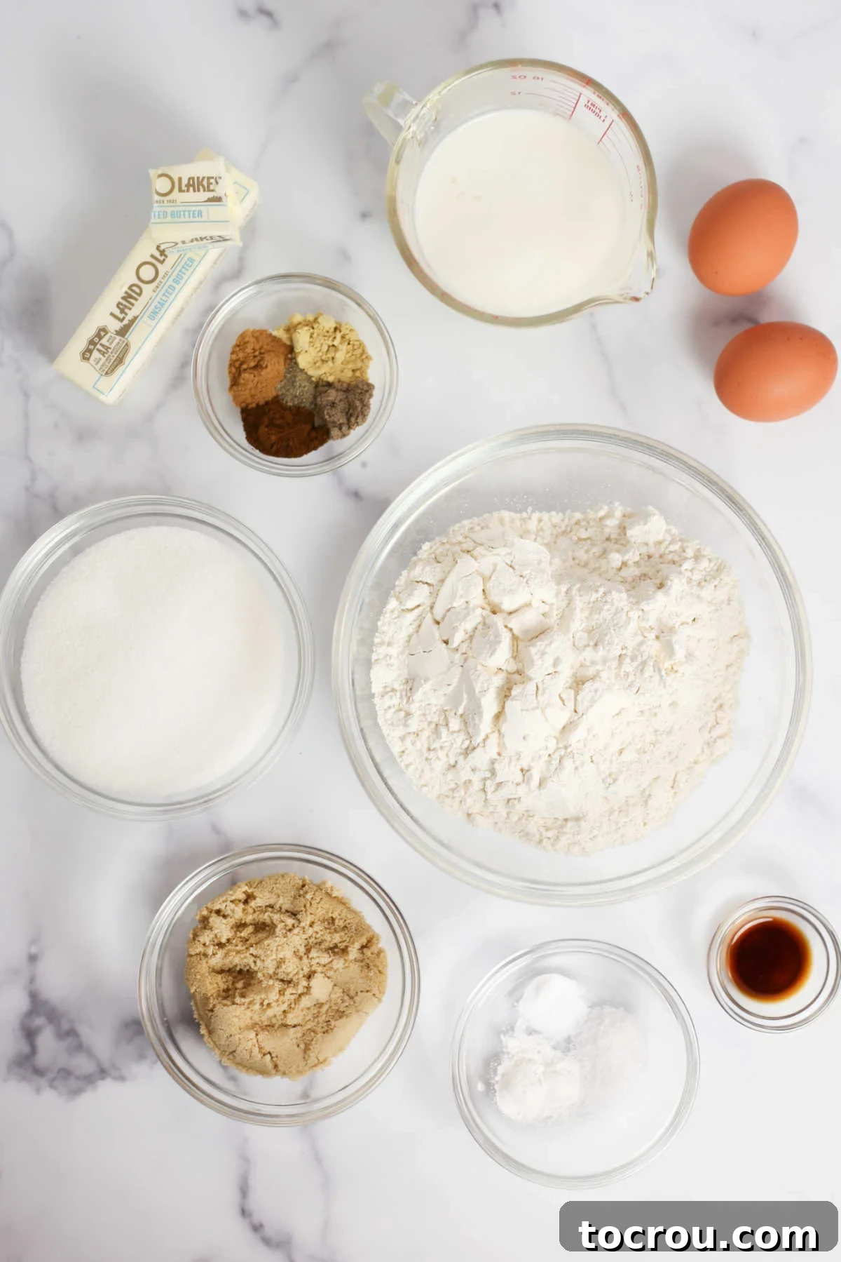 Assorted chai bundt cake ingredients laid out, including flour, spices, butter, eggs, and sugar, ready for mixing.