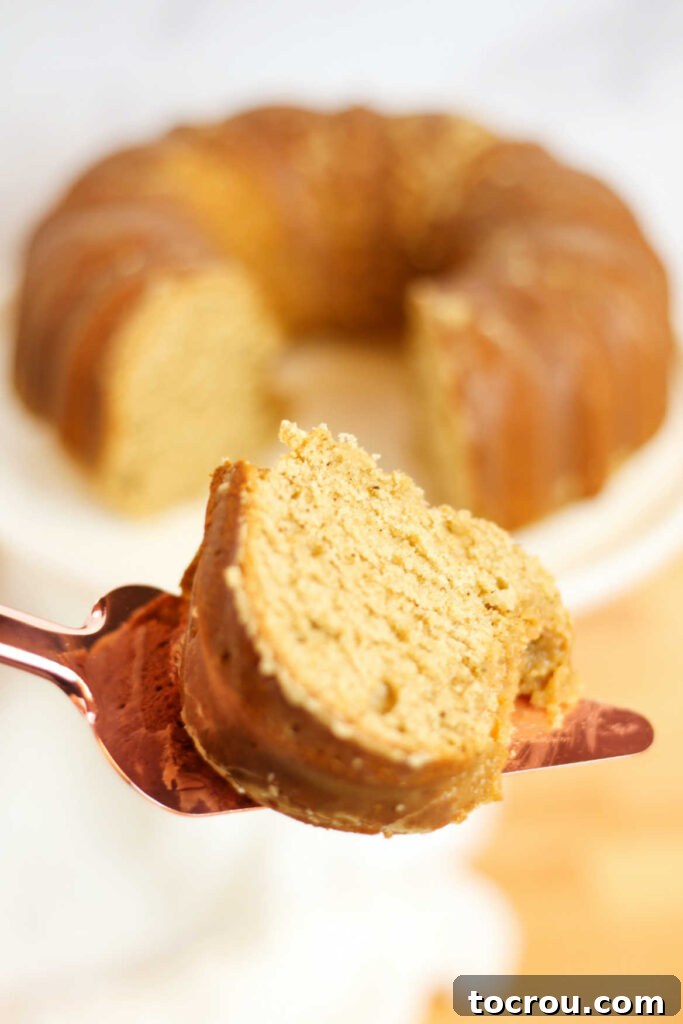A slice of chai spiced bundt cake is gently lifted on a spatula, showcasing its moist texture and perfect shape.