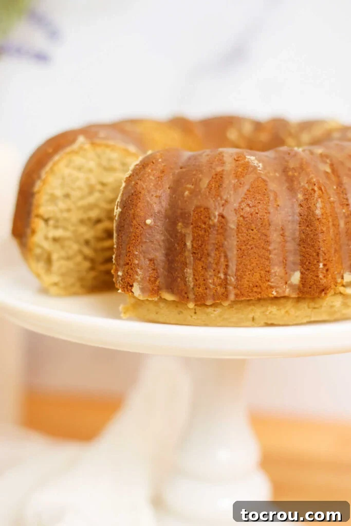 A close-up view of a chai bundt cake adorned with a delicate espresso glaze, presented on a platter with one slice already taken, highlighting the appealing interior.