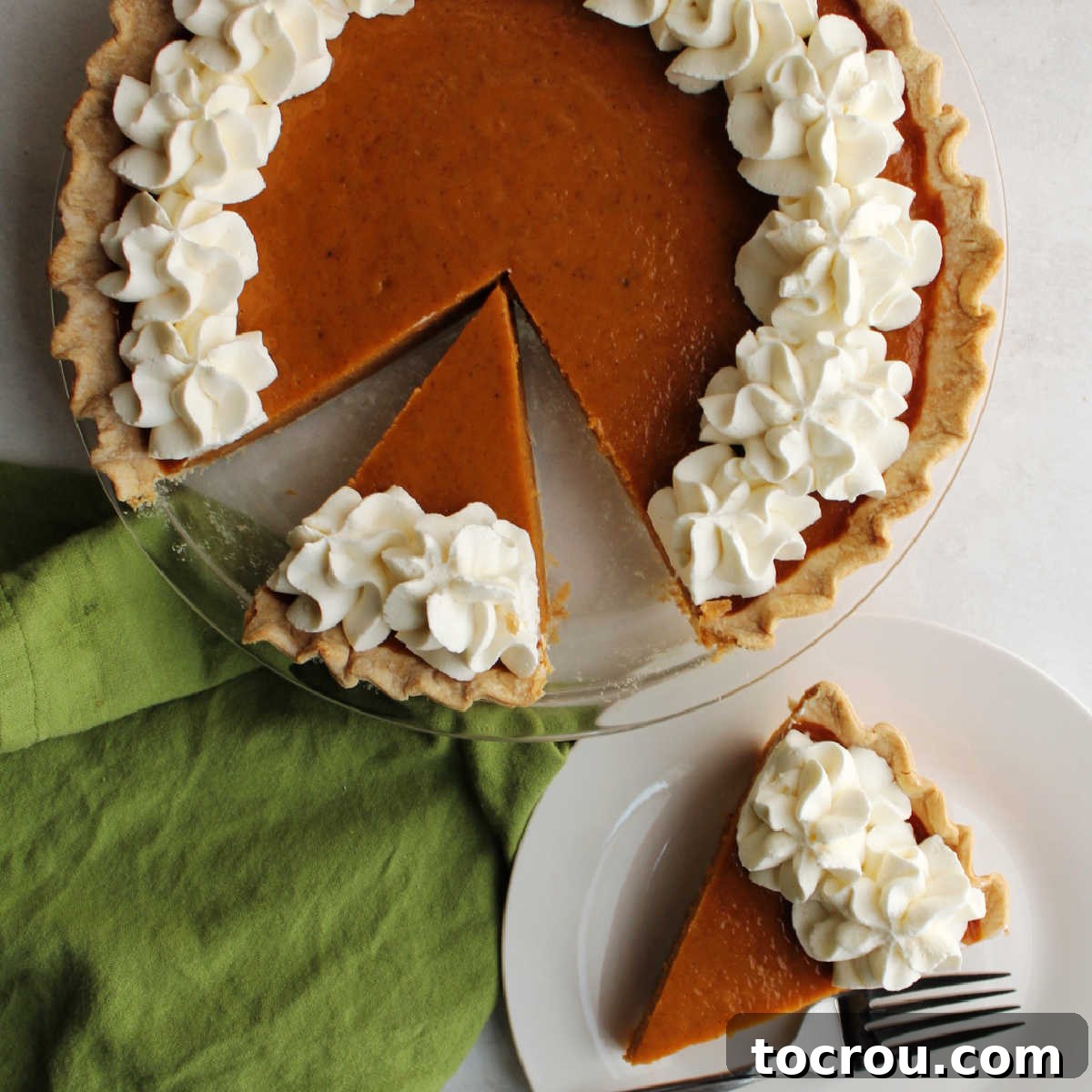 Simple & Creamy Pumpkin Pie with Sweetened Condensed Milk A delectable slice of pumpkin pie, beautifully topped with swirls of homemade whipped cream, resting beside the remaining whole pie, ready to be devoured.