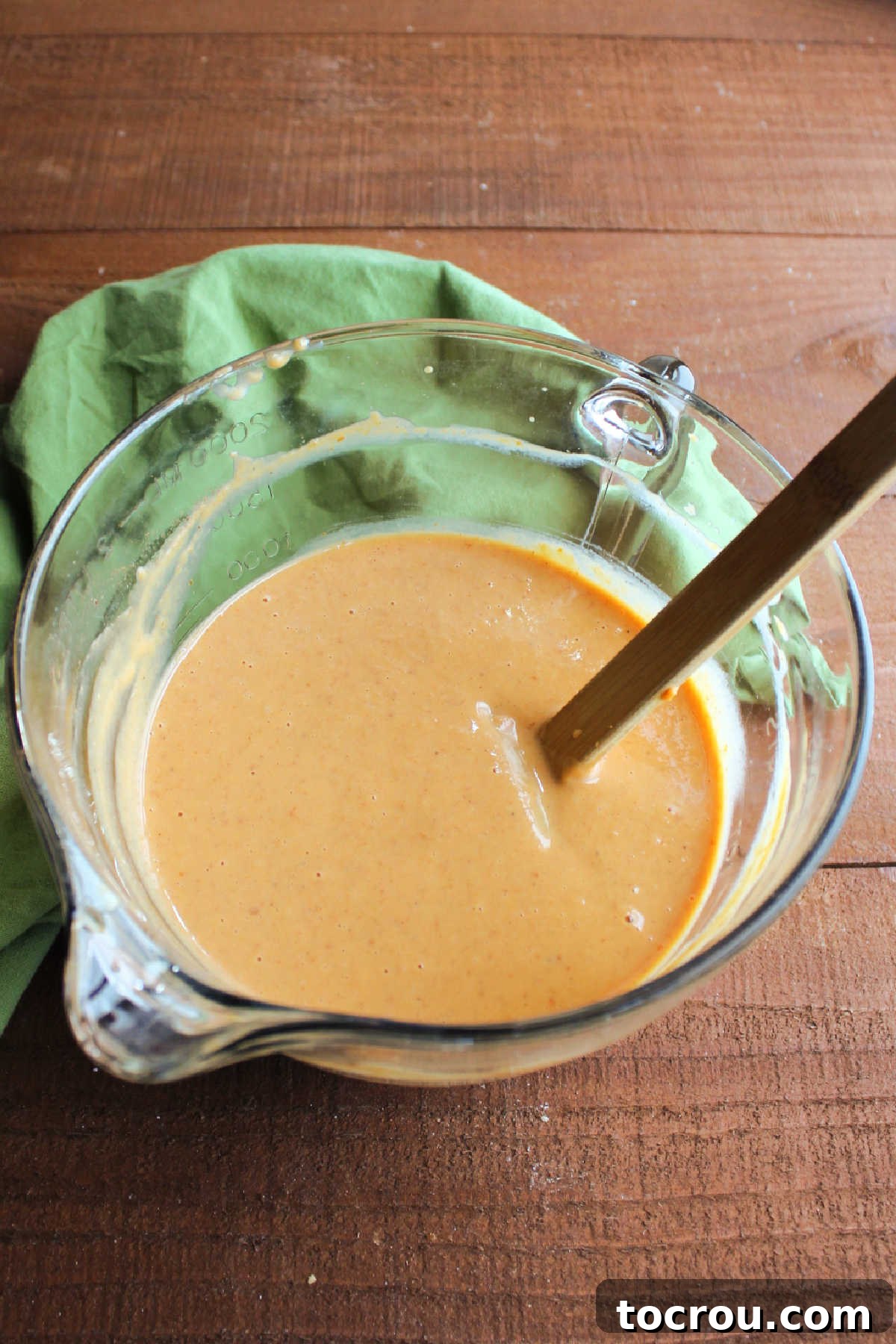 Preparing the Creamy Pumpkin Pie Filling A mixing bowl brimming with the smooth, vibrant orange pumpkin pie filling, perfectly blended and ready to be poured into the waiting pie crust.