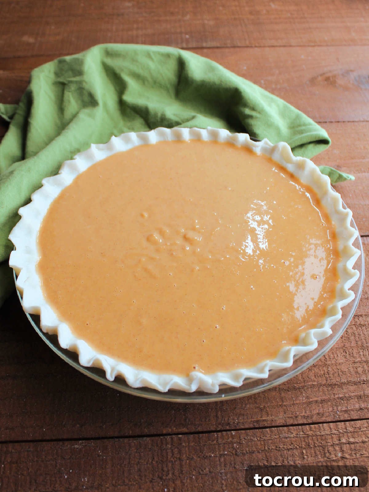 Ready to Bake: Uncooked Pumpkin Pie The unbaked pumpkin pie mixture, a harmonious blend of condensed milk, eggs, spices, and pumpkin, nestled within a raw pie crust, poised for its transformation in the oven.
