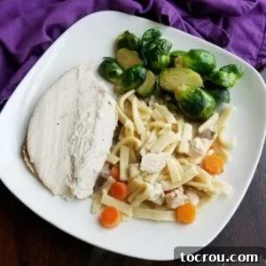 Dinner plate with roasted brussels sprouts, sliced turkey breast, and homemade chicken and egg noodles with carrots.