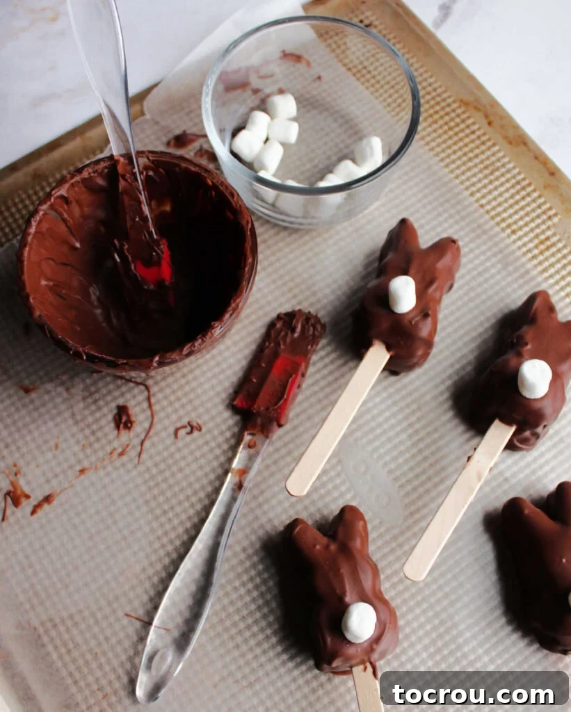 Chocolate coated marshmallow bunnies setting up on wax paper.