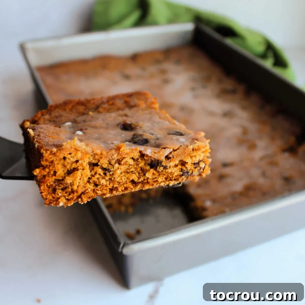 Vintage Poor Man's Cake First Slice Lifting the first piece of moist, spiced raisin poor man's cake out of a baking pan, showing its rich brown color and tender crumb.