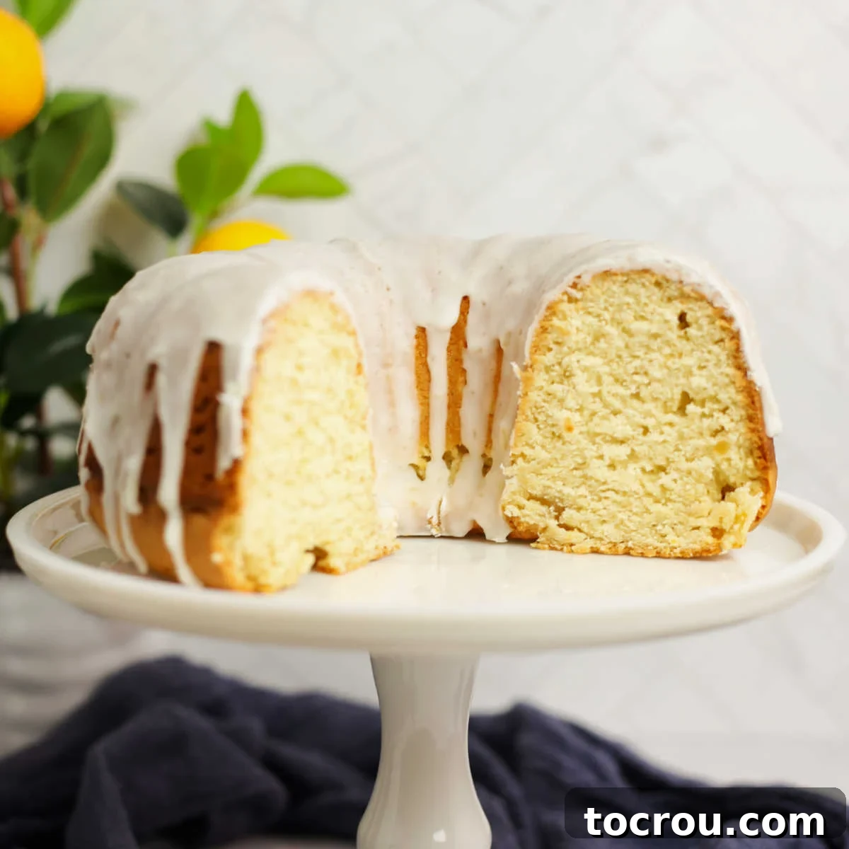 Sun-Kissed Lemon Bundt with Ginger Drizzle 2 Two-thirds of a lemon Bundt cake with white ginger lemon glaze, revealing its soft yellow interior.