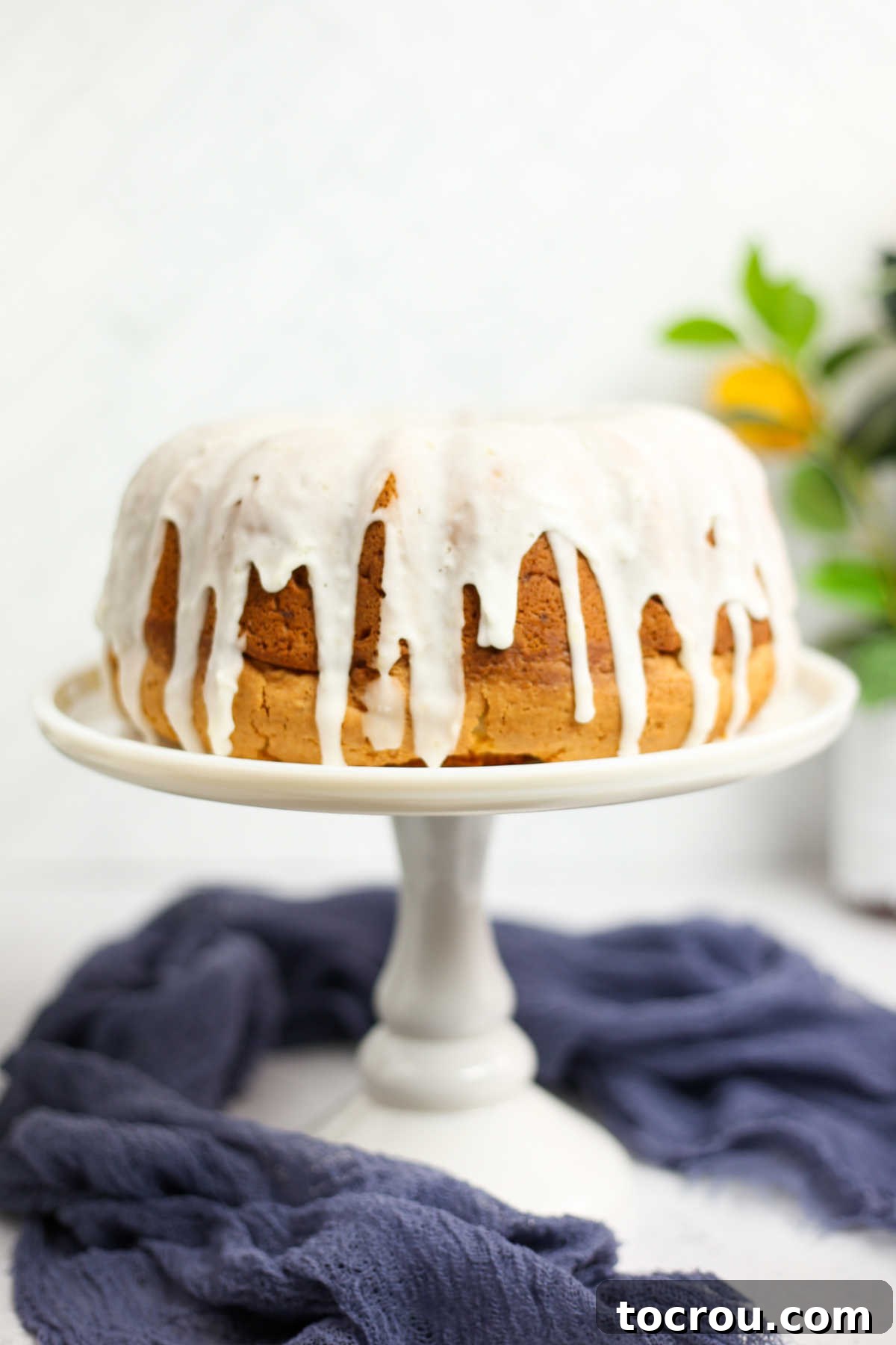 Sun-Kissed Lemon Bundt with Ginger Drizzle 5 A whole lemon Bundt cake with a glossy white lemon ginger glaze, presented on a cake stand.